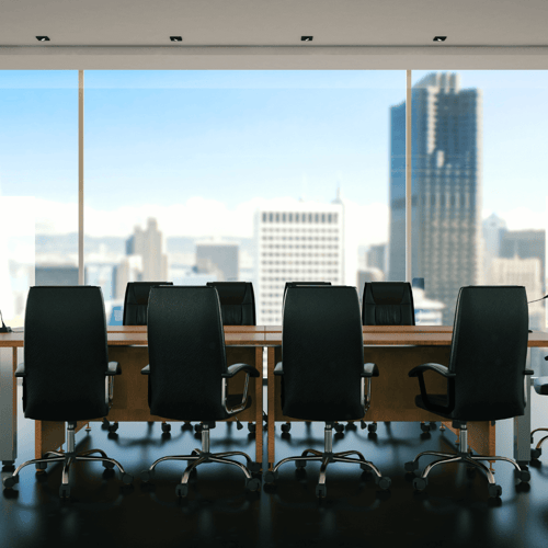 An empty boardroom looking over the city through large windows